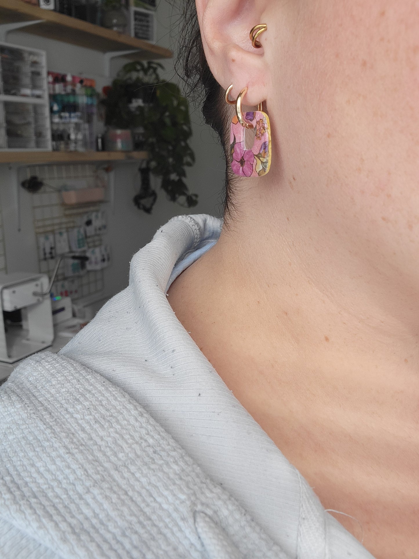 Close-up of a person wearing a floral earring with a blurred background