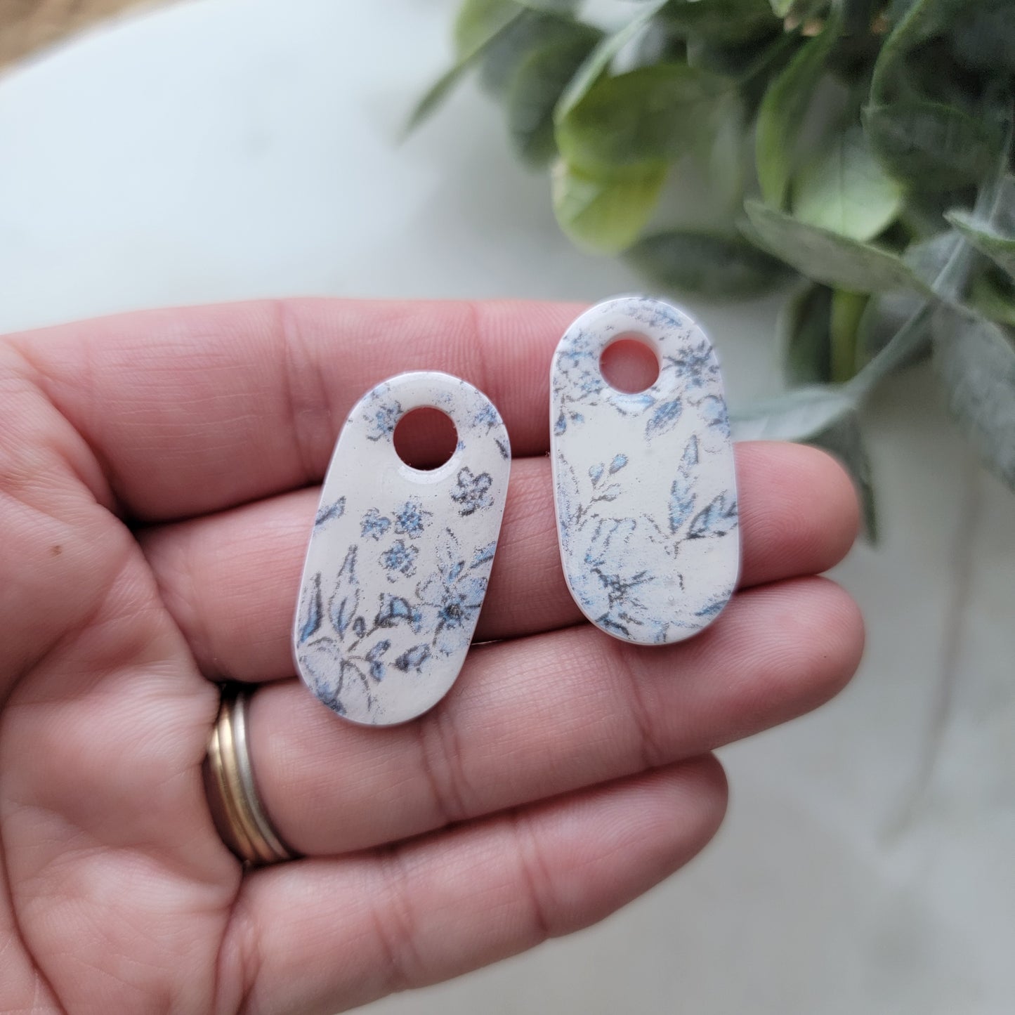 Two floral-patterned tags held in a hand with a light background
