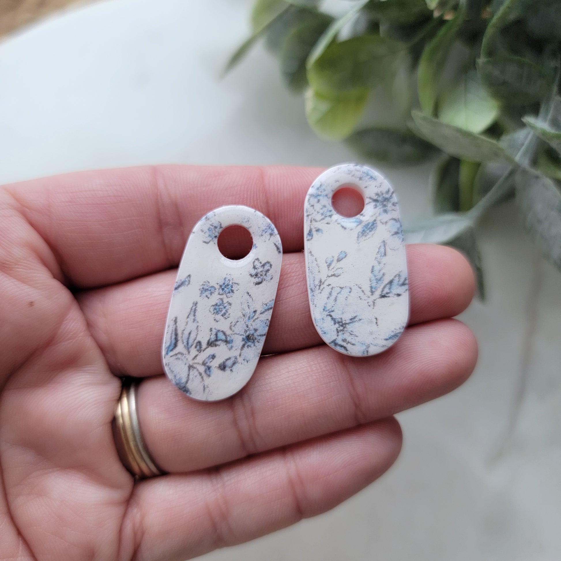 Two floral-patterned tags held in a hand with a light background