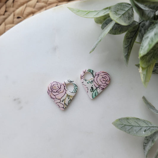 Floral earrings on a white surface with green leaves in the background