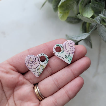 Hand holding two floral-patterned ceramic animal figurines with a light background.