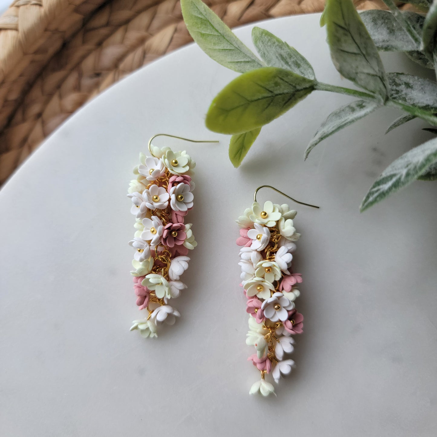 Pink, yellow and white flowers decorated earrings on a white background.
