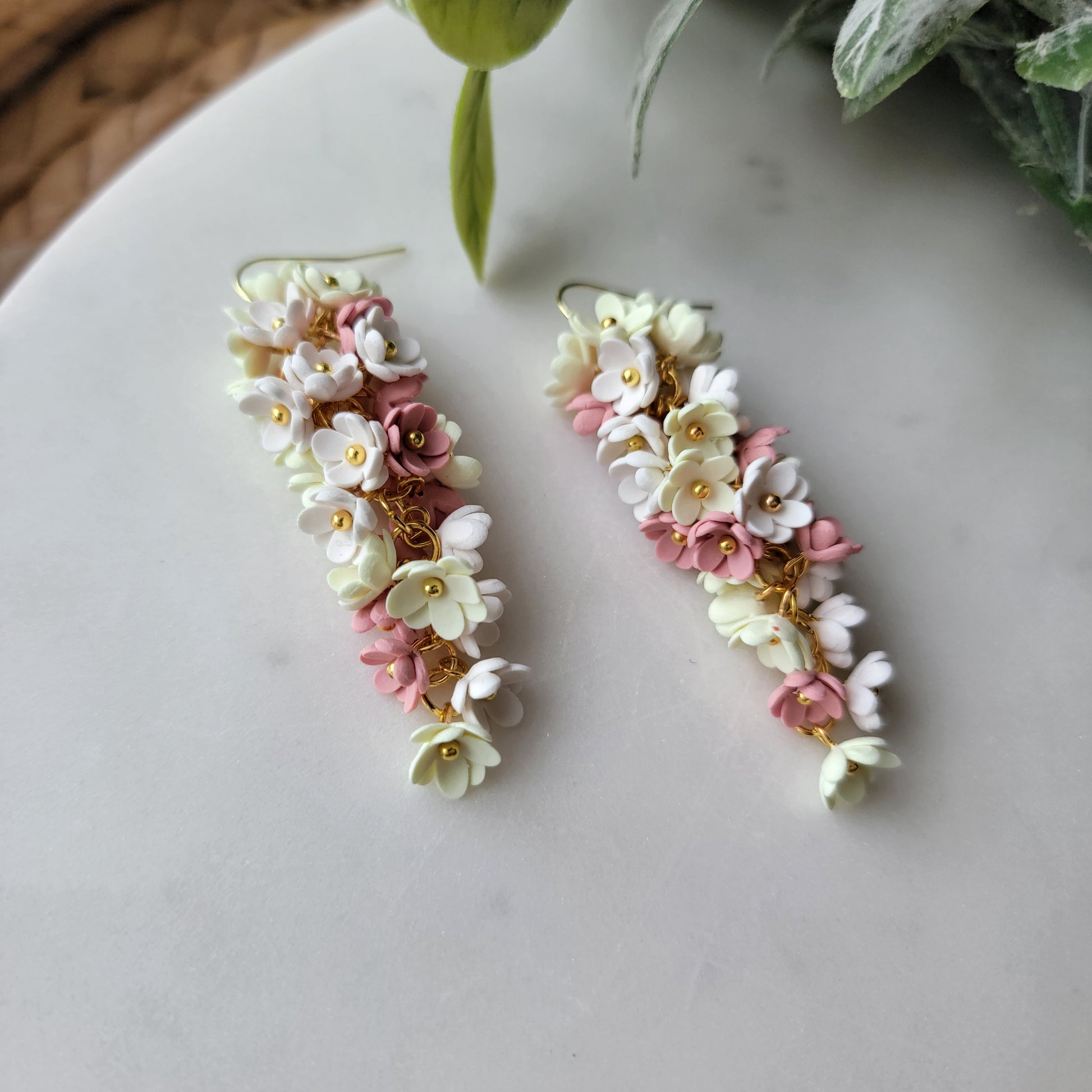 Pink, yellow and white flowers decorated earrings on a white background.