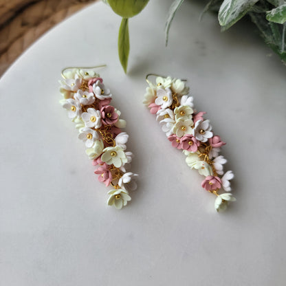Pink, yellow and white flowers decorated earrings on a white background.