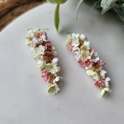 Pink, yellow and white flowers decorated earrings on a white background.