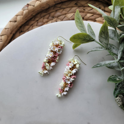Pink, yellow and white flowers decorated earrings on a white background.
