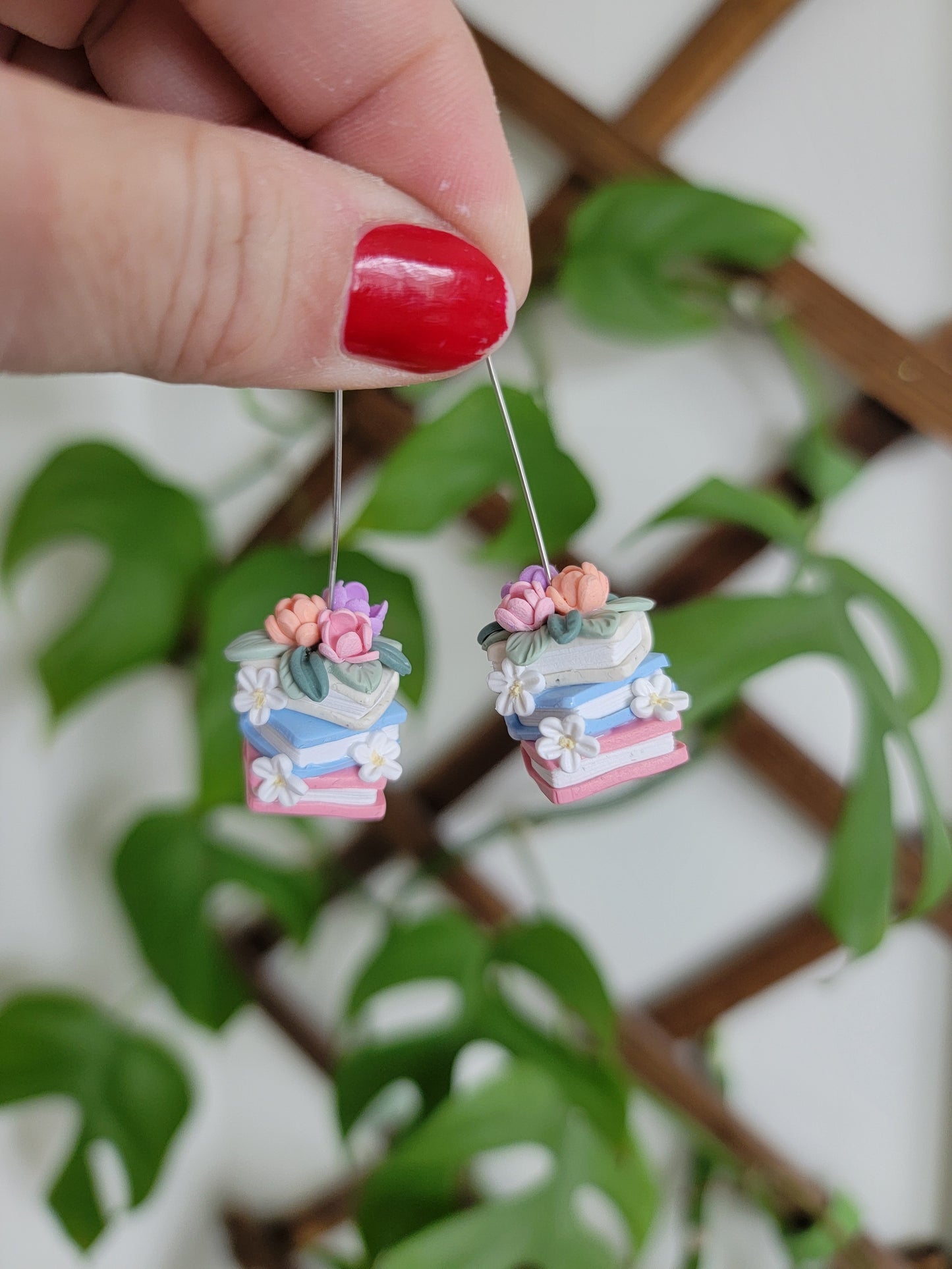 A set of colorful book earrings in a stack covered in dainty flowers.