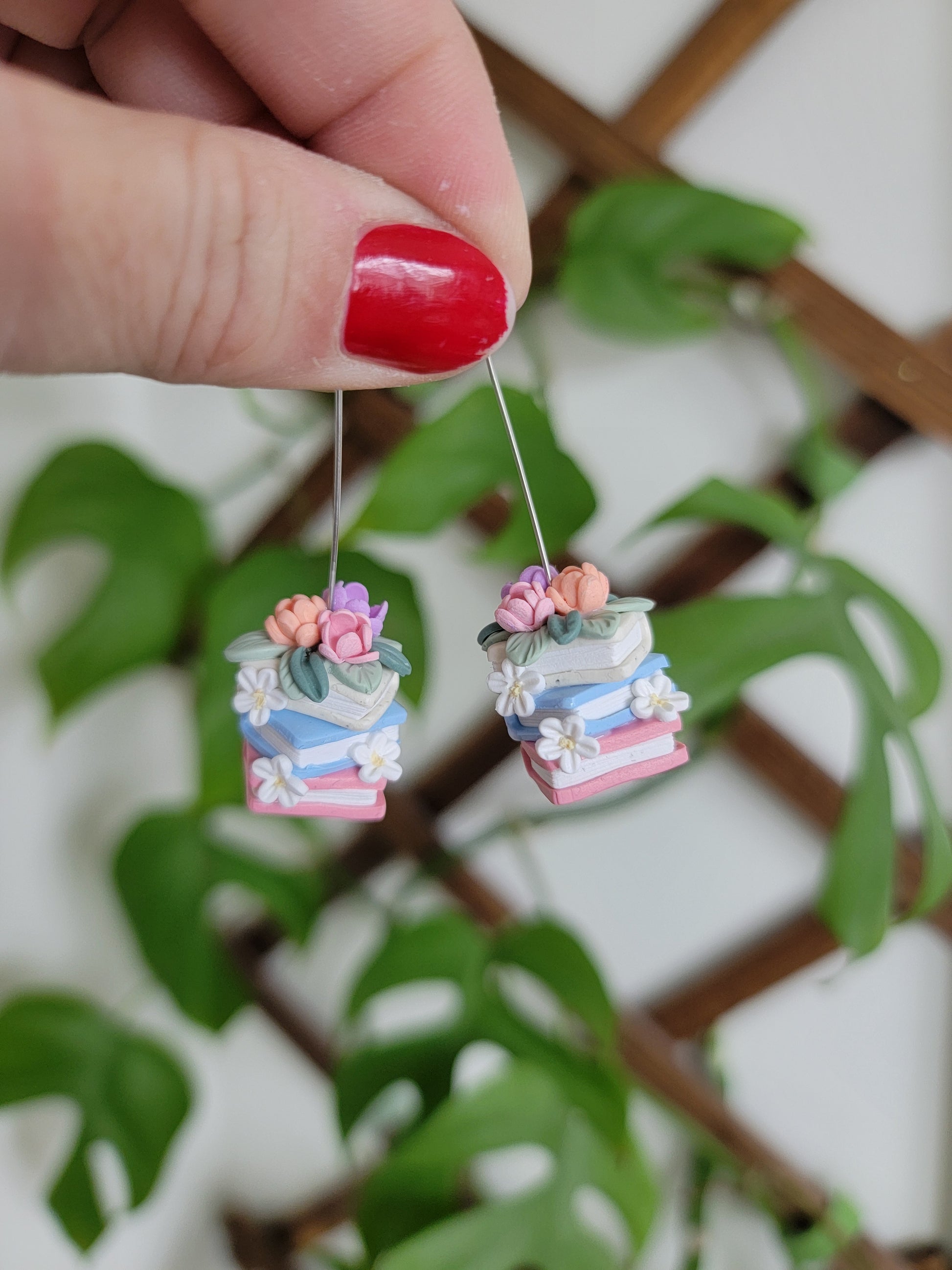 A set of colorful book earrings in a stack covered in dainty flowers.