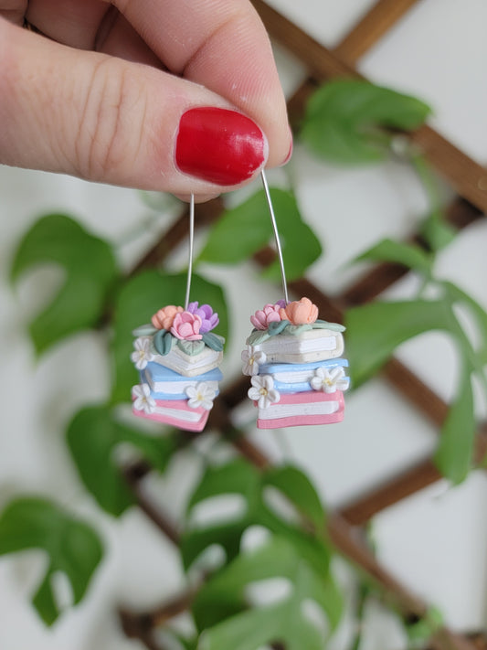 A set of colorful book earrings in a stack covered in dainty flowers.
