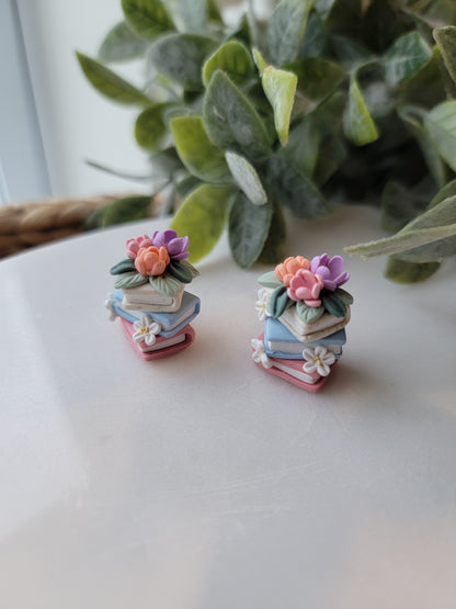 A set of colorful book earrings in a stack covered in dainty flowers.