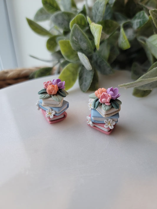 A set of colorful book earrings in a stack covered in dainty flowers.