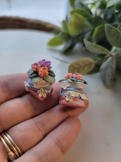A set of colorful book earrings in a stack covered in dainty flowers.