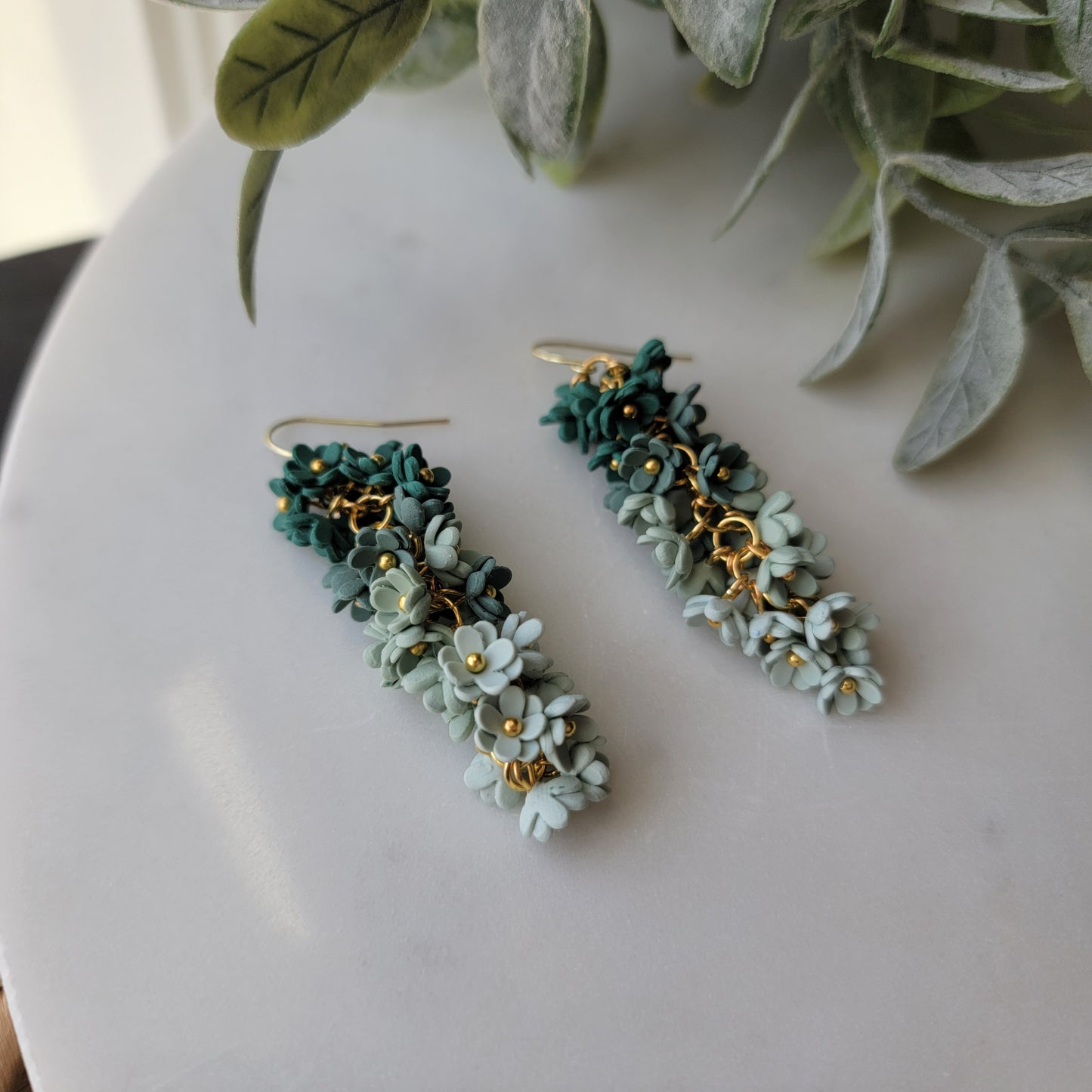Green floral earrings on a white background.