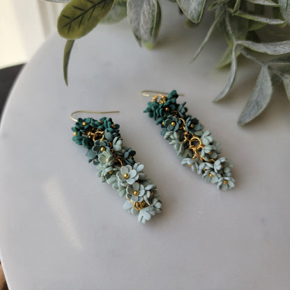 Green floral earrings on a white background.