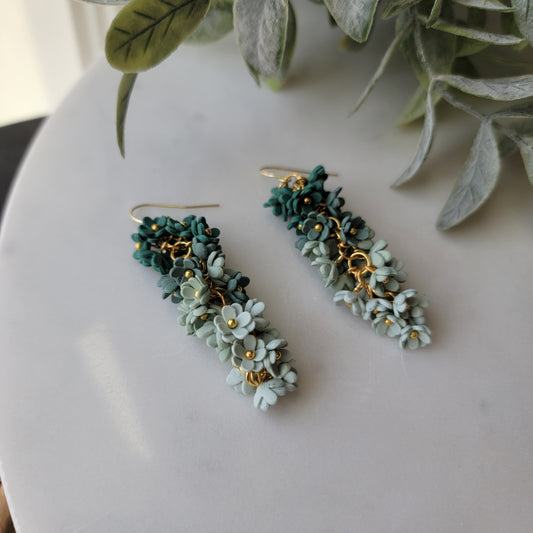Green floral earrings on a white background.